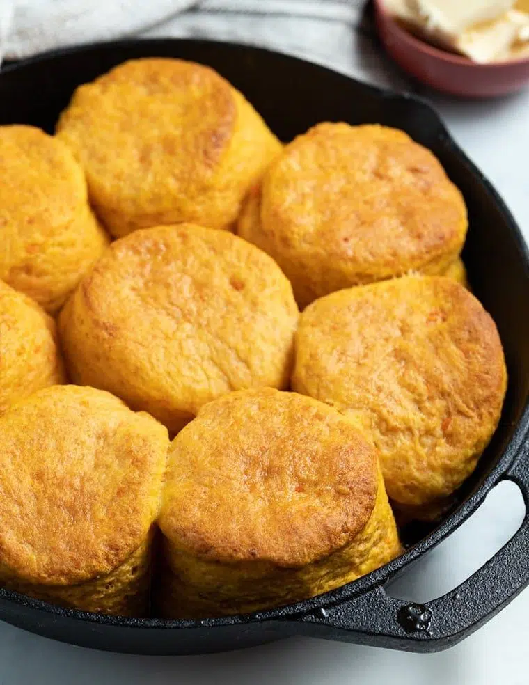 black pan with eight golden vegans sweet potato biscuits on a white table