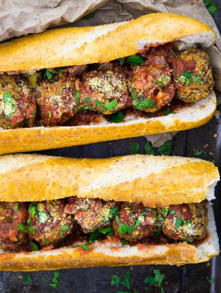 close up of two homemade vegan meatball subs on parchment paper
