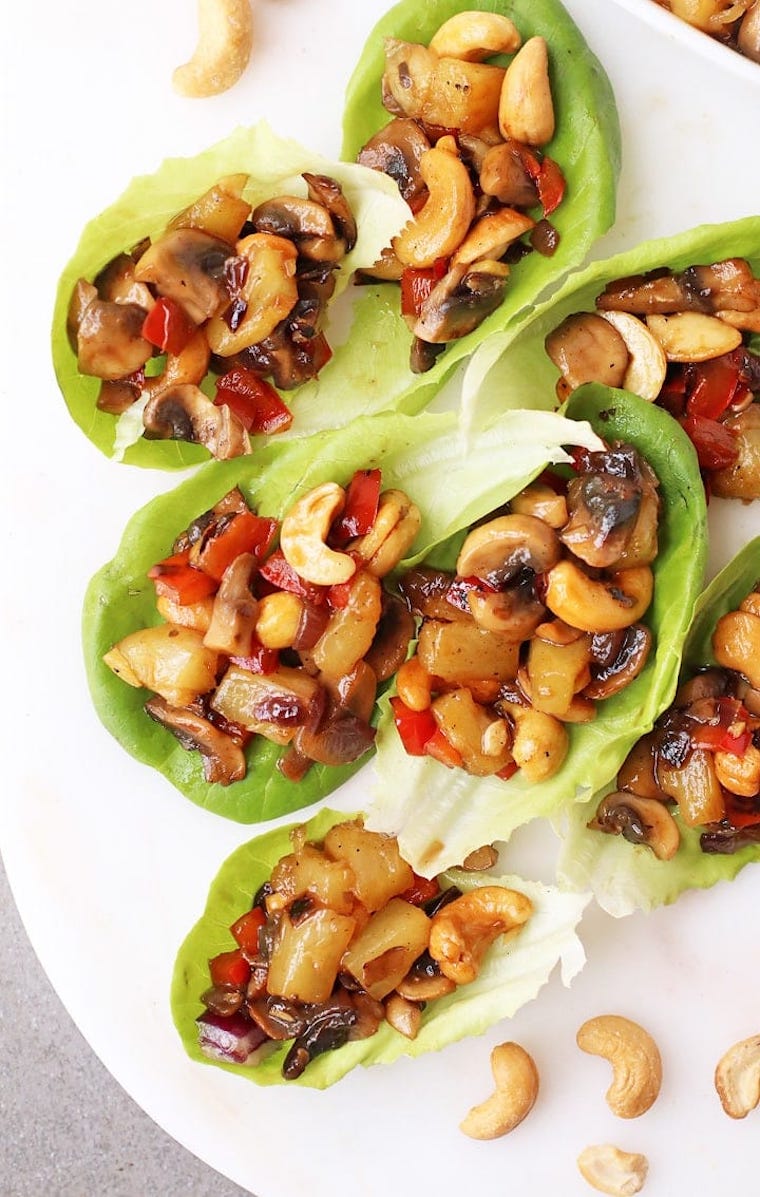 white plate with small lettuce wraps filled with teriyaki flavored veggies and cashews