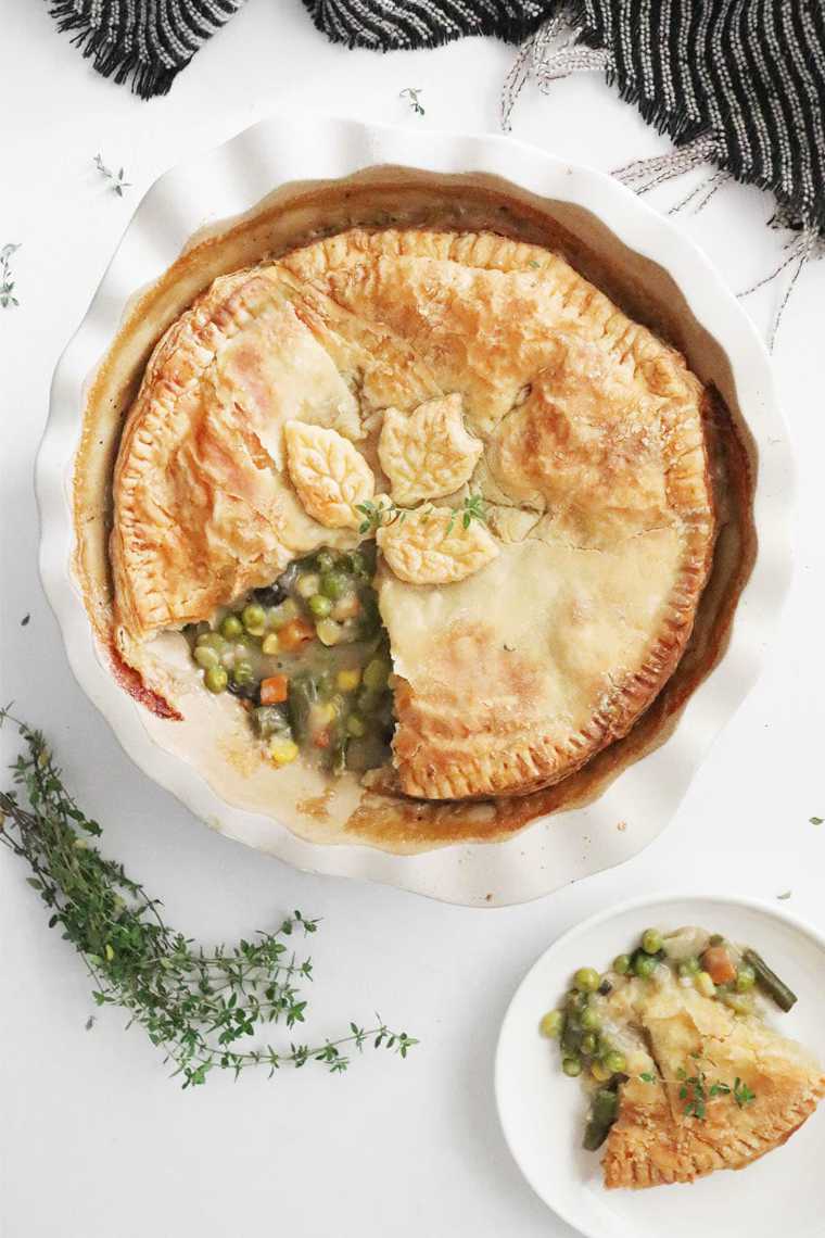 white baking dish with a vegan pot pie, one piece taken out on a small plate