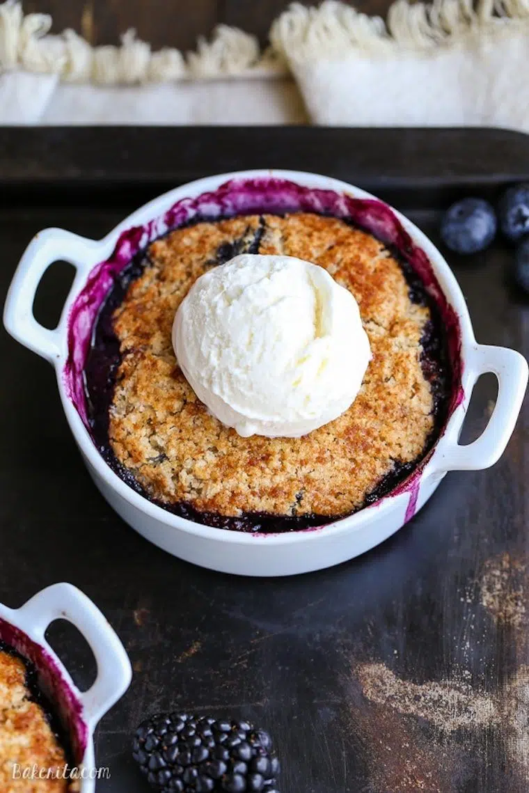 small round white baking dish with a vegan southern blackberry cobbler topped with ice cream