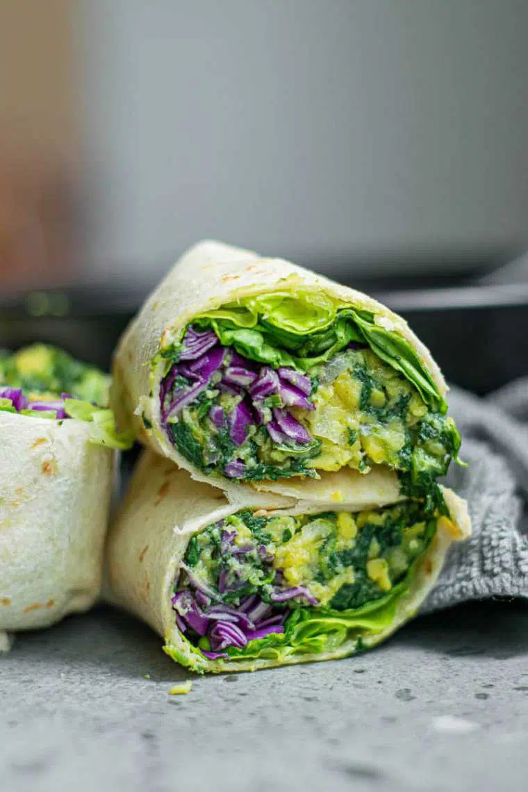 grey table with four homemade green vegan breakfast burritos for a portable lunch or snack