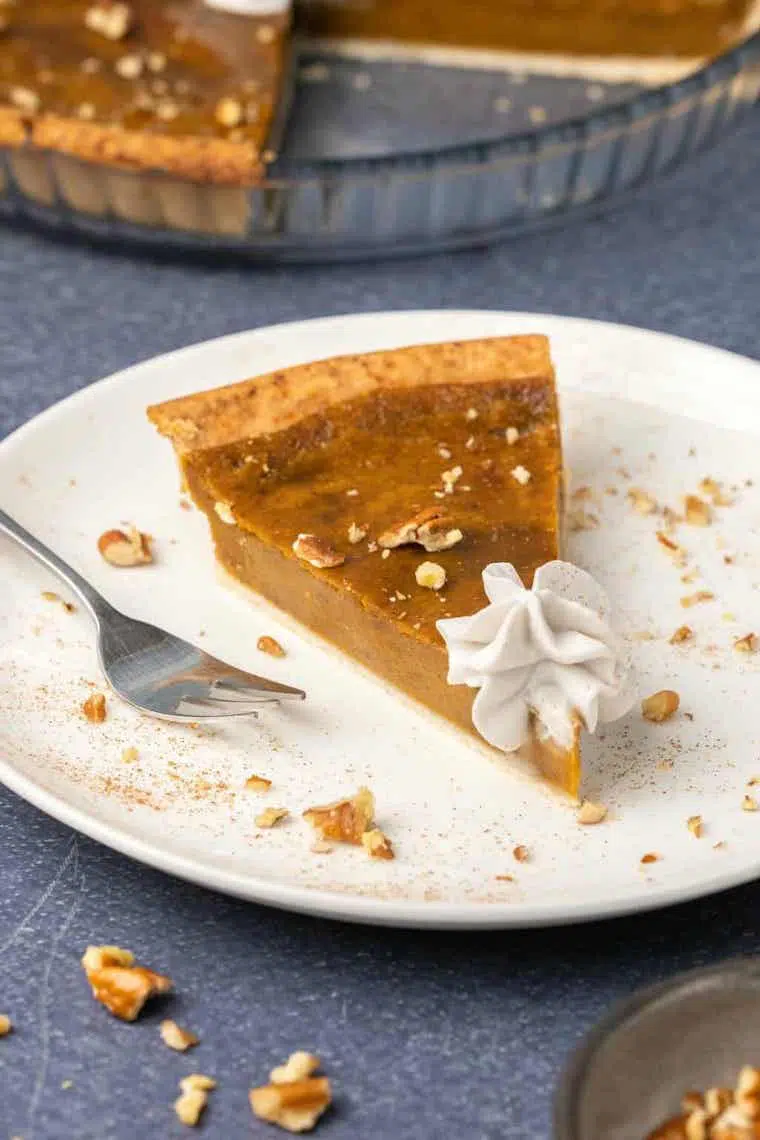 one slice of delicious vegan sweet potato pie on a white plate with vegan whipped cream