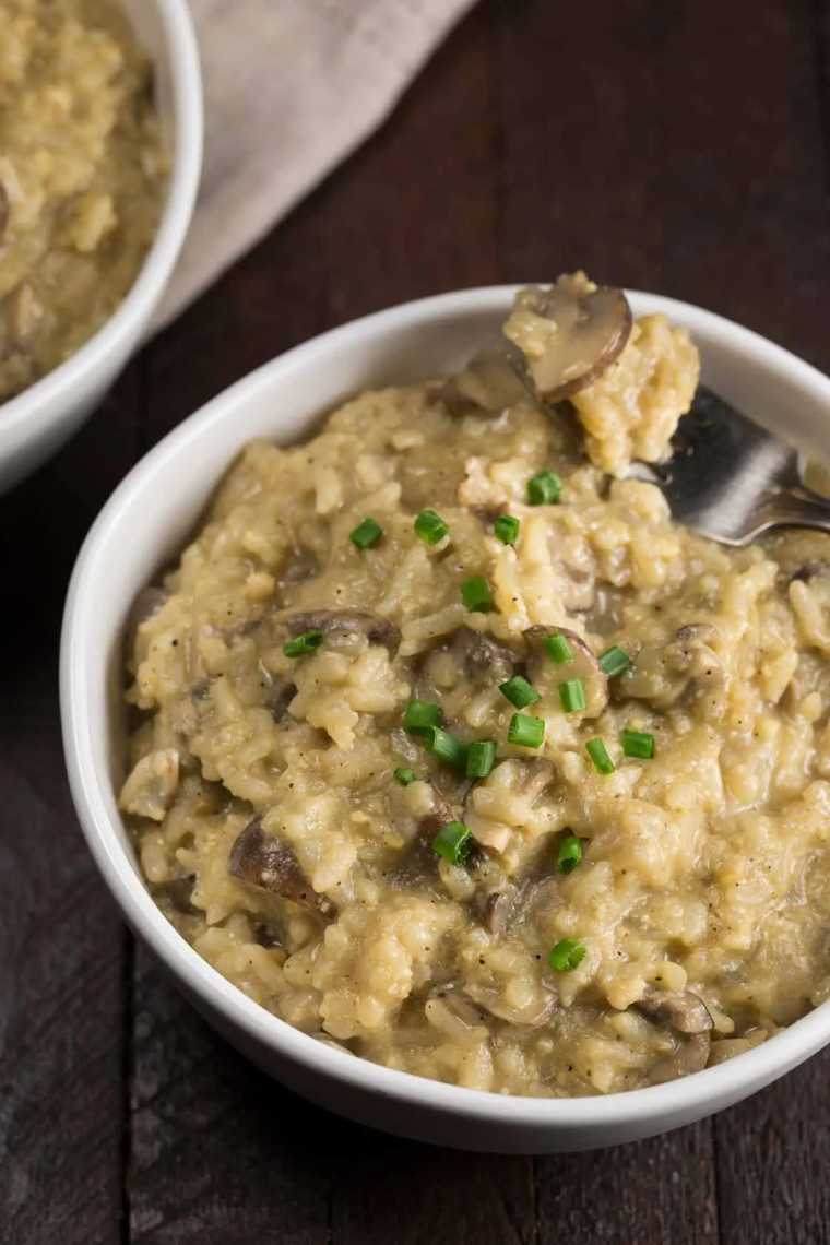 two white bowls with Instant Pot Vegan Mushroom Risotto and a fork