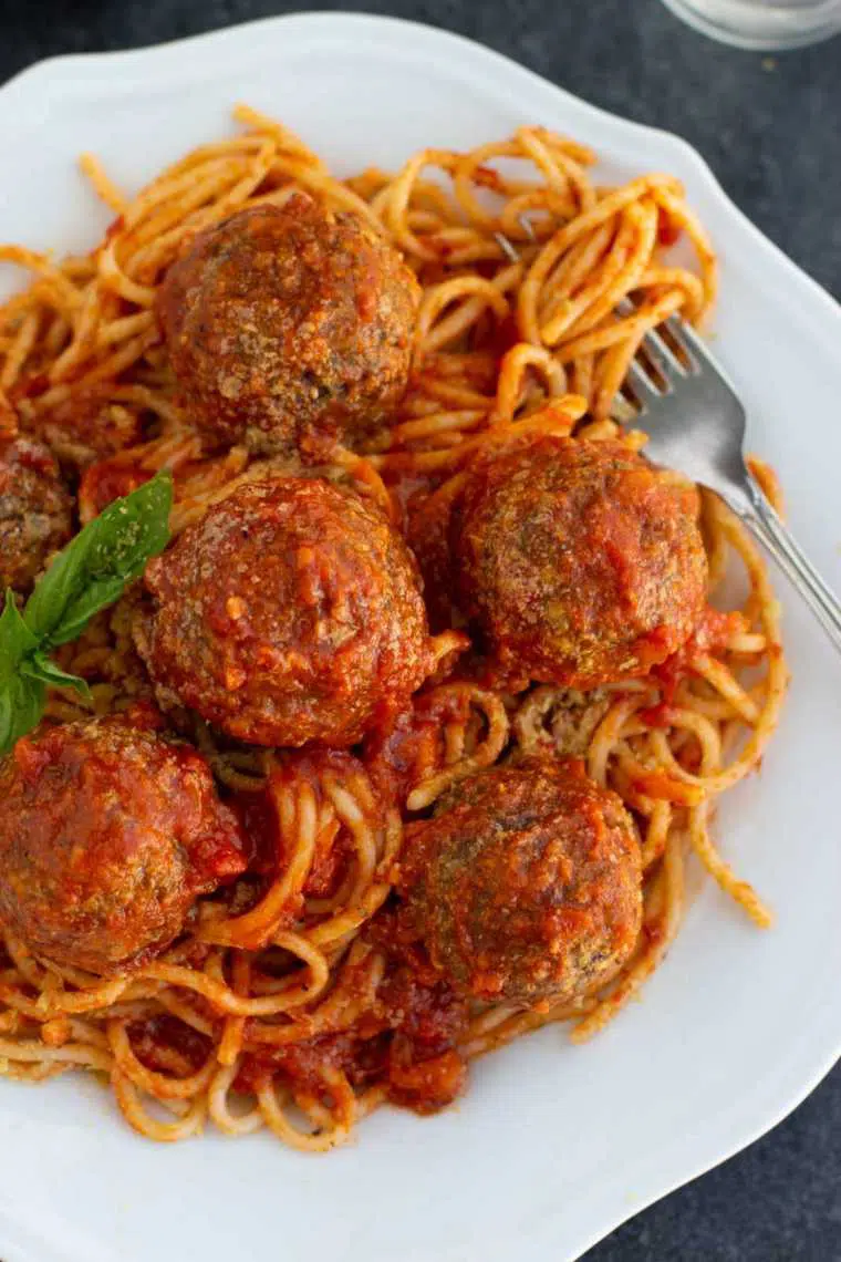 white plate with spaghetti and vegan meatballs in tomato sauce