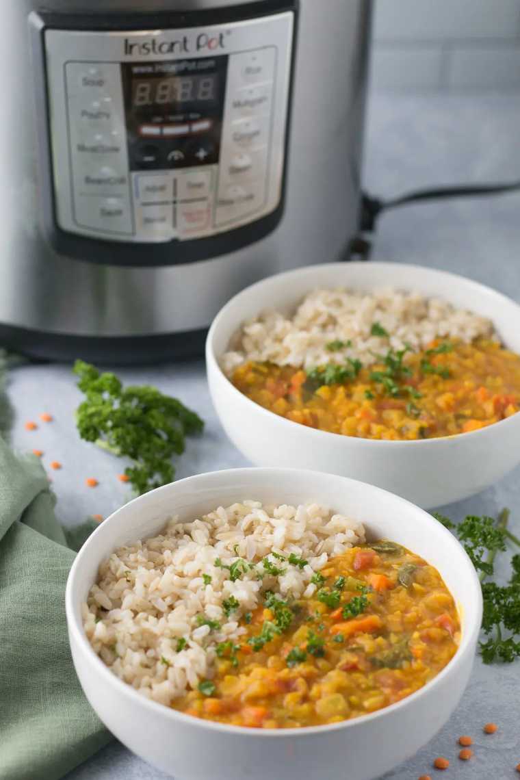 Instant Pot on a table next to two white bowls filled with rice and vegan dal