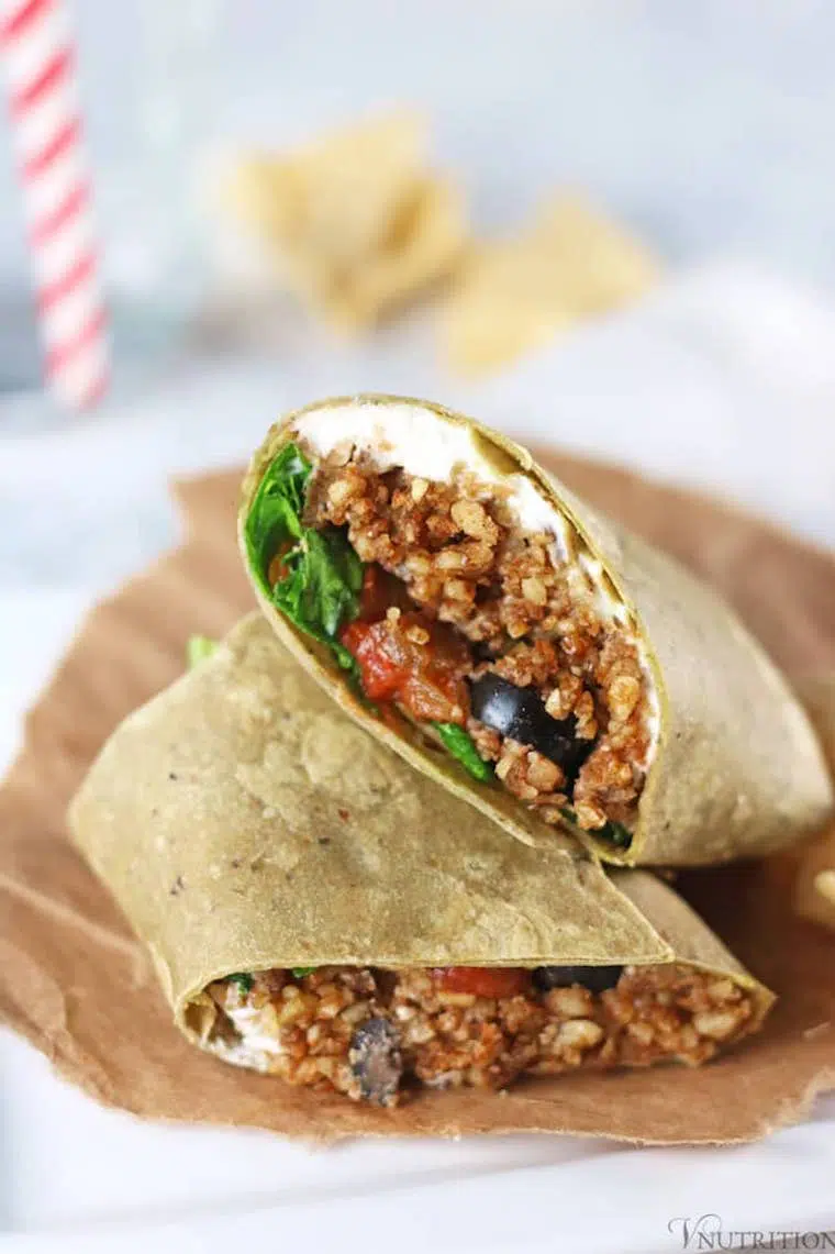 parchment paper on a table with two walnut taco filled vegan wraps on top of each other