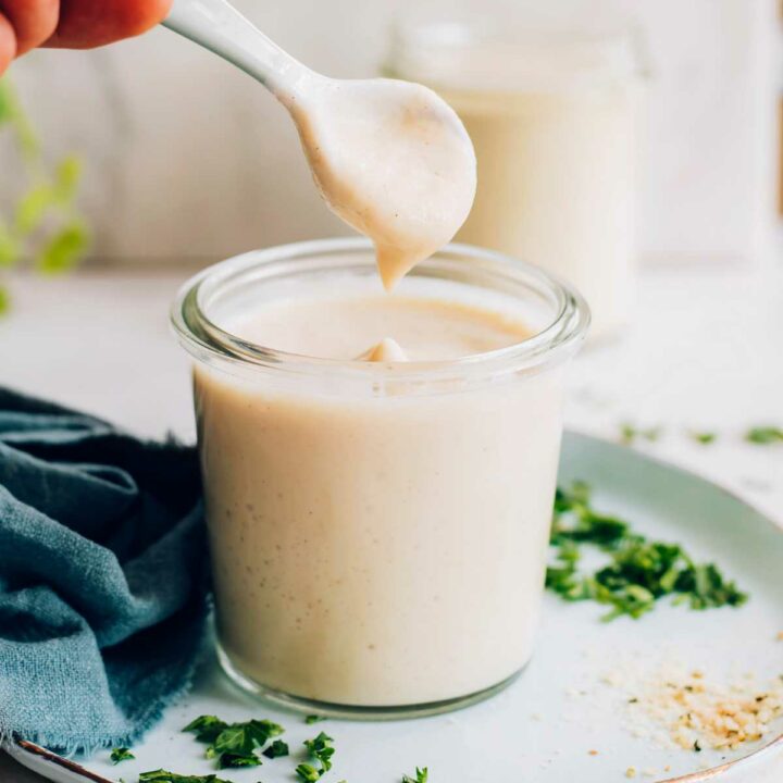 Vegan Alfredo Sauce on a spoon dripping into a glass