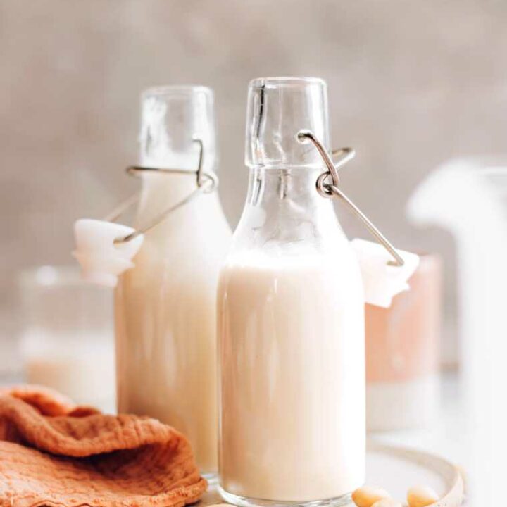 two glass bottles on a table filled with homemade almond creamer