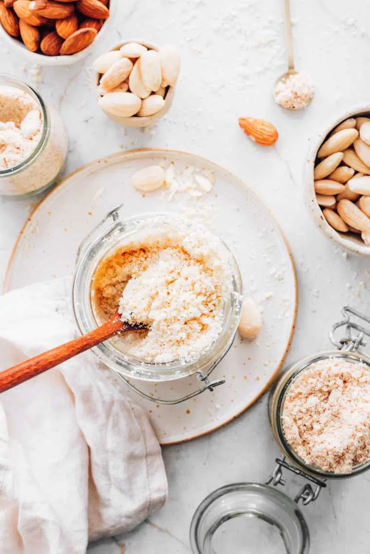 homemade almond flour in glass jar on a table next to whole almonds