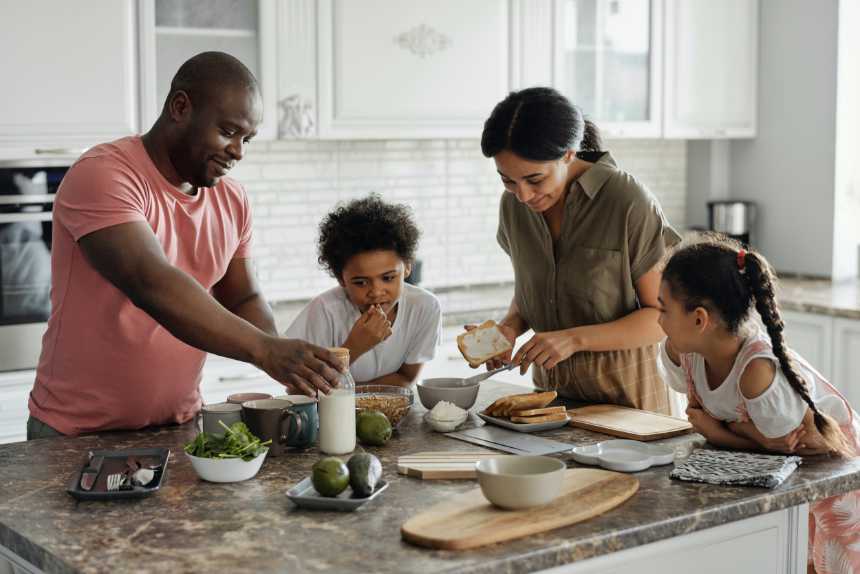 plant-based family of four standing around a table and preparing food