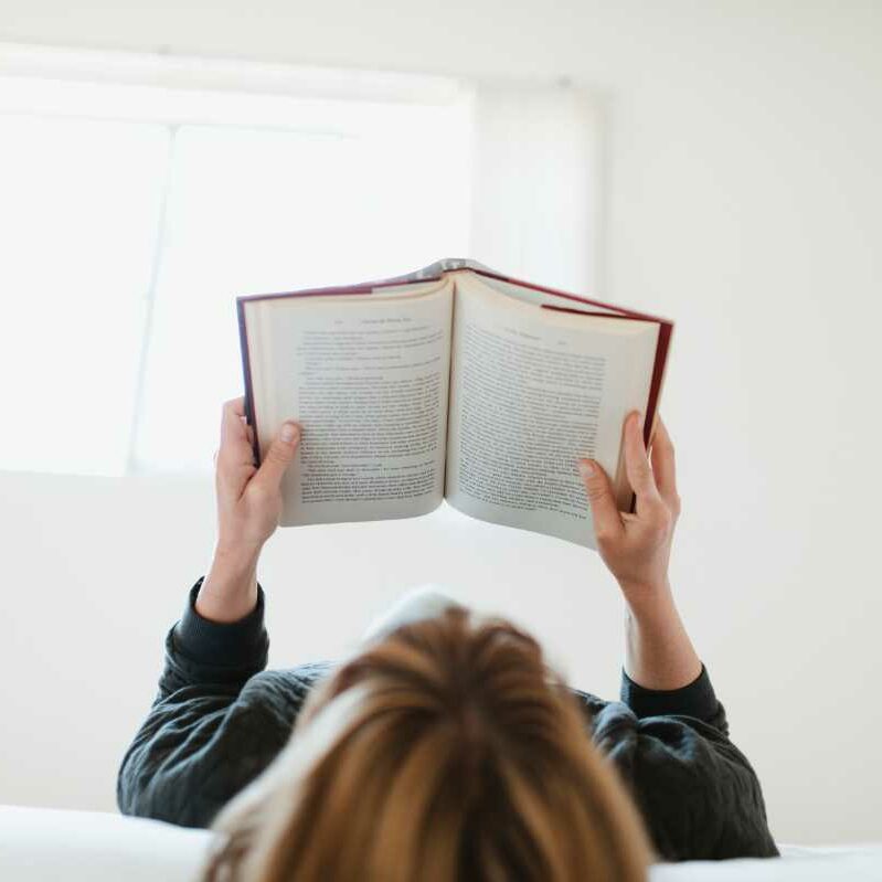 Woman reading a vegan book in her bed