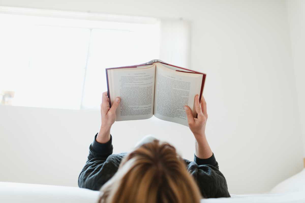 Woman reading a vegan book in her bed