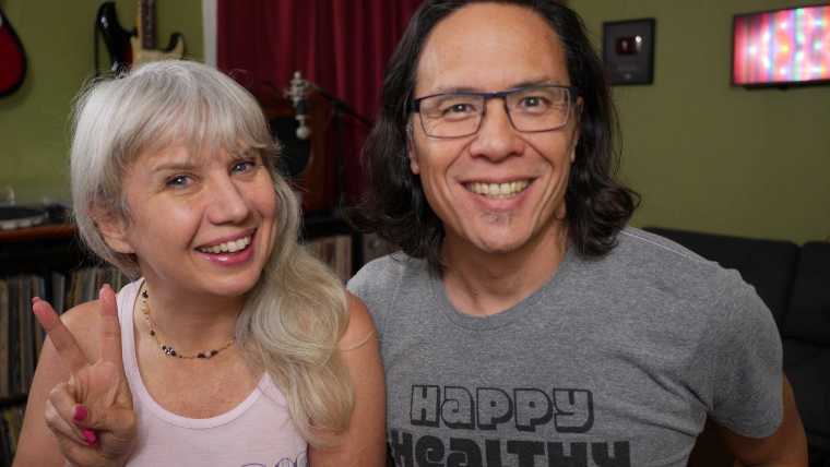 Anji and Ryan from Happy Healthy Vegan standing next to each other in their studio smiling