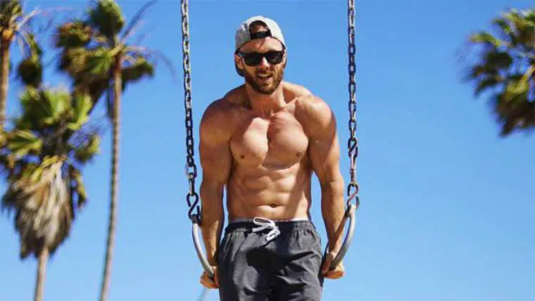 Derek from Simnett Nutrition with cap and sunglasses doing calisthenics on metal ropes showing his muscular body