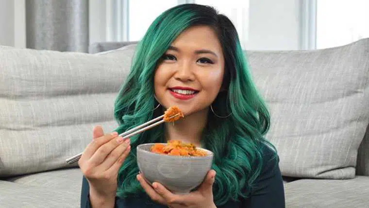 Rose from Cheap Lazy Vegan smiling and eating a colorful dish with chopsticks