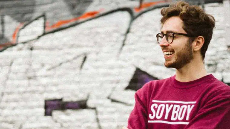 Jack from Humane Hancock in front of graffitied wall with red "Soyboy" jumper