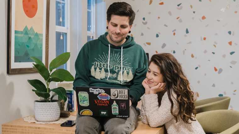 Jasmine and Chris from Sweet Simple Vegan sitting next to each other and looking on laptop screen