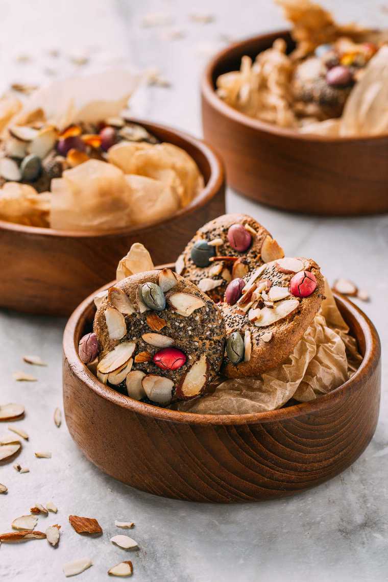 three wooden bowls with parchment paper and vegan birds nest cookies