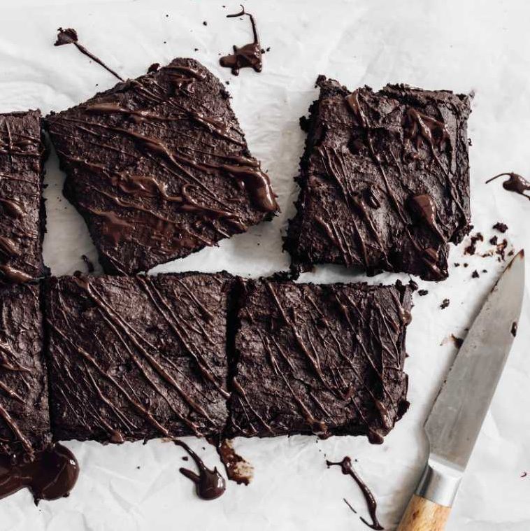 white parchment paper with six black bean brownie squares next to a knife