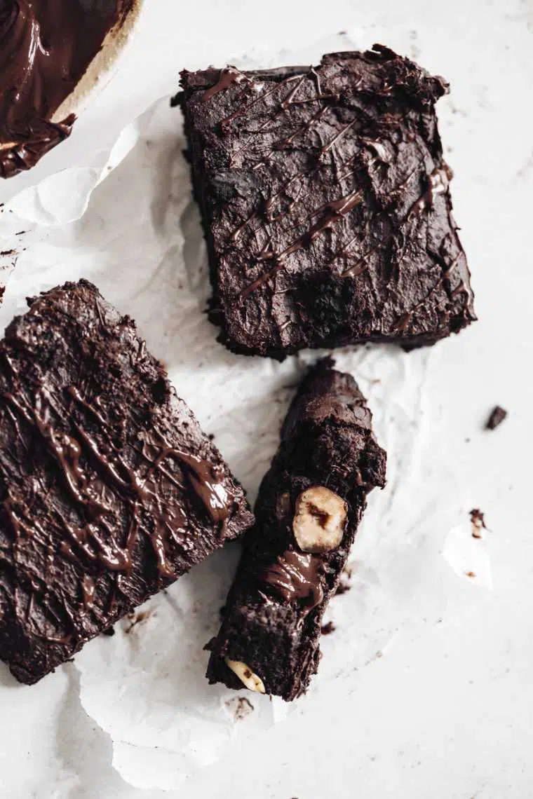 three vegan brownies on white parchment paper