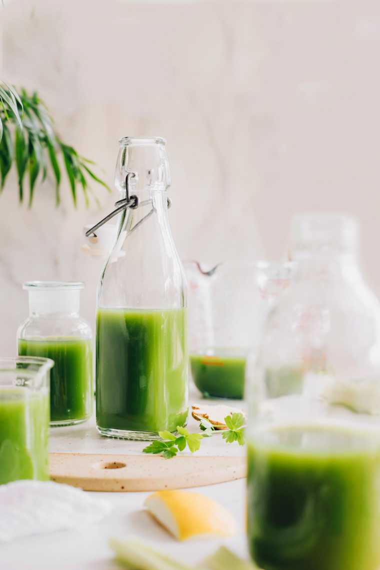 homemade green juice on table in bottles and glasses