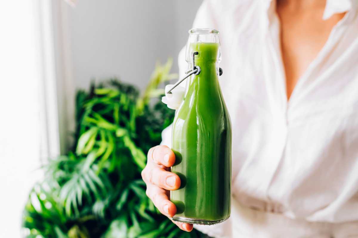 woman holding a bottle of green juice made in a blender
