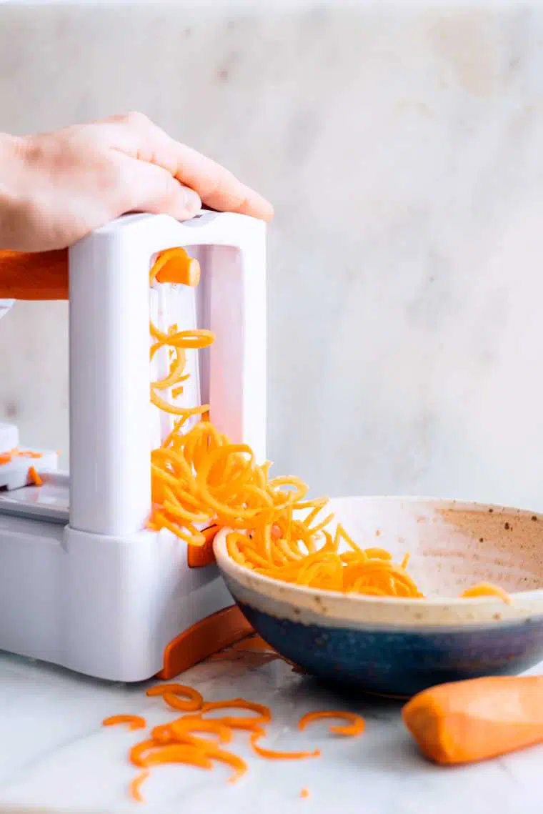 woman creating spiralized carrots on a kitchen table