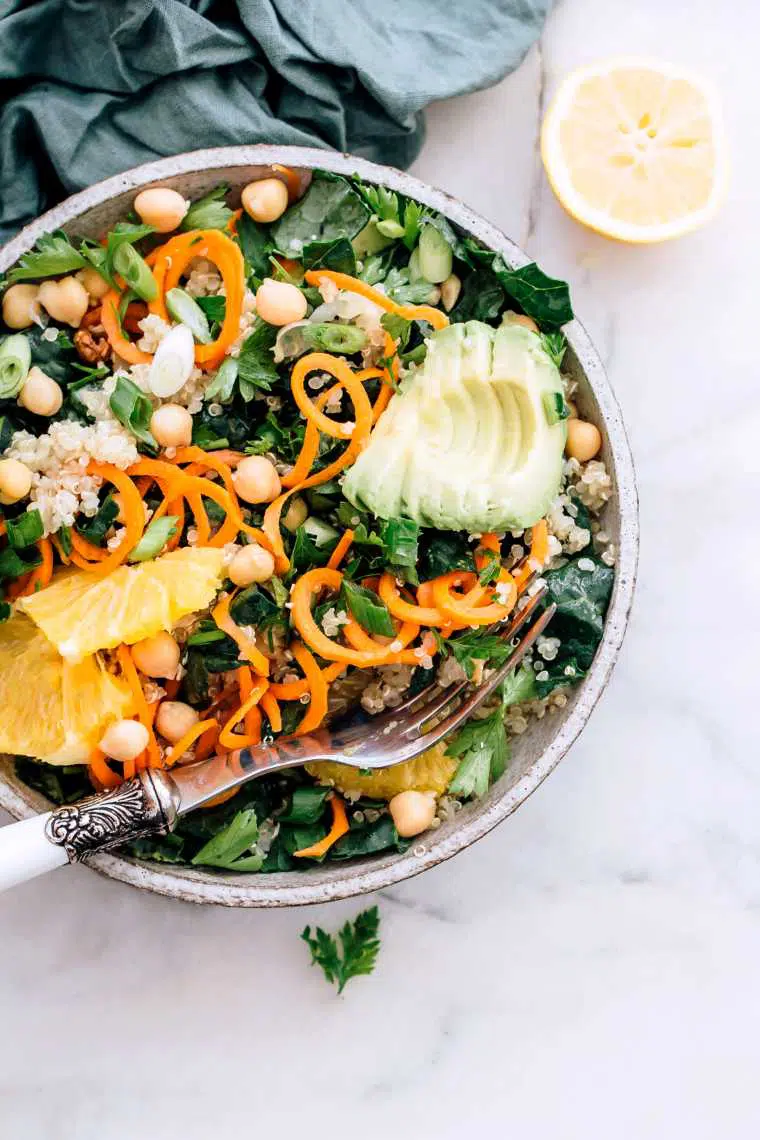 bowl with spiralized carrot, sliced avocado, cooked quinoa, chickpeas, leafy greens and a fork