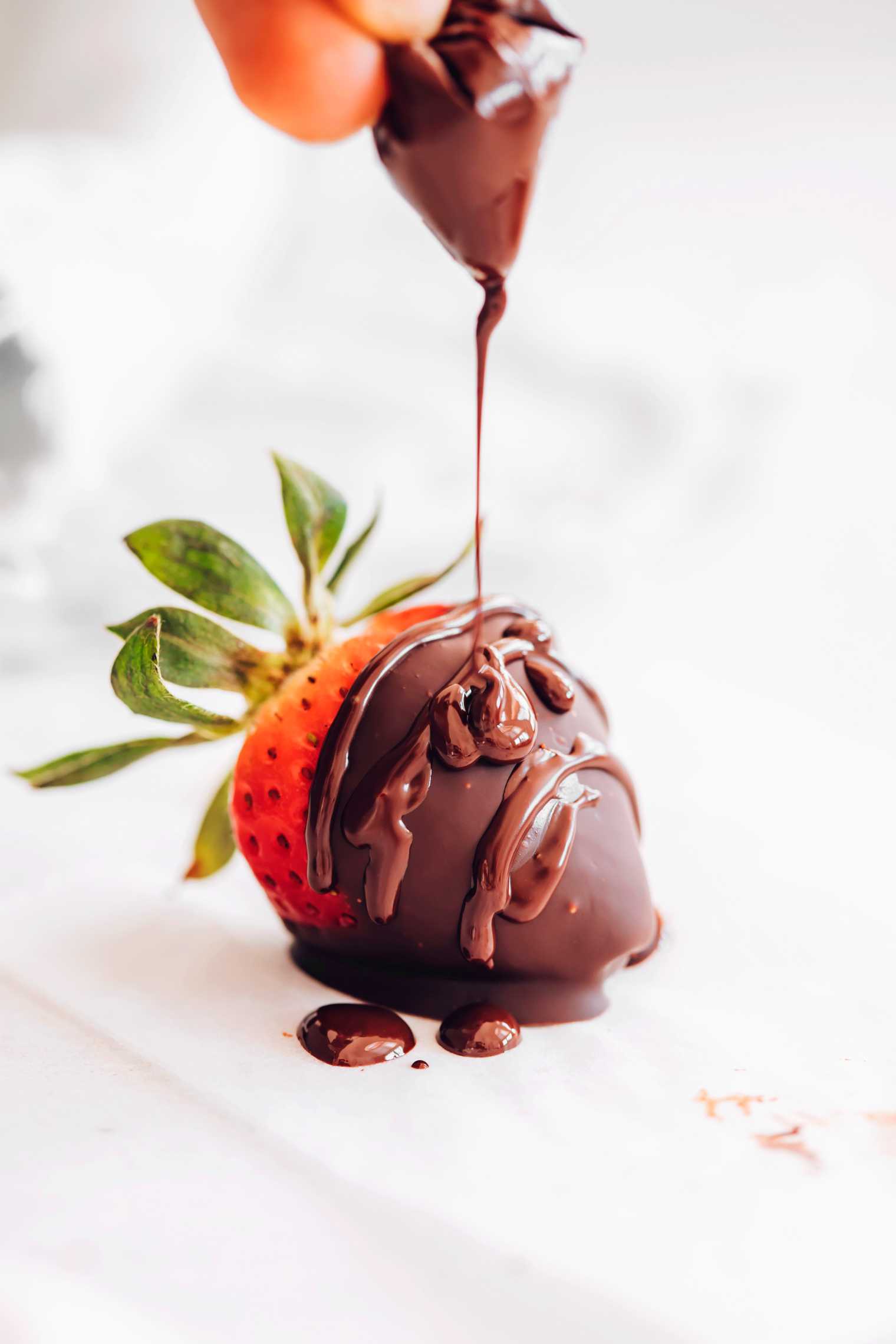 fresh dipped strawberry being drizzled with melted chocolate