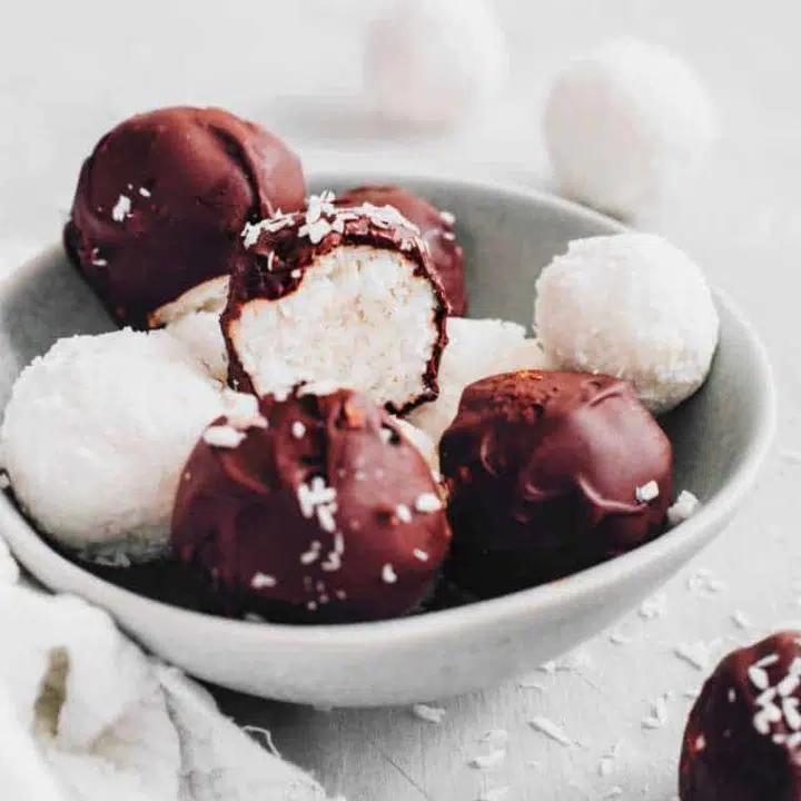 small bowl with a handful of chocolate covered coconut bliss balls