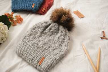 three handmade vegan-friendly beanies on a bed next to some flowers
