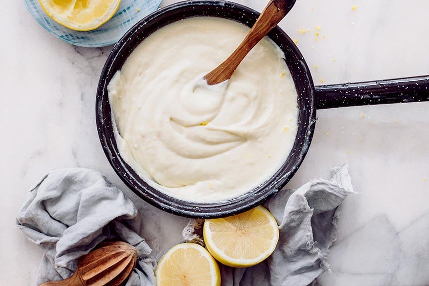 creamy vegan custard in a black pan next to some lemons