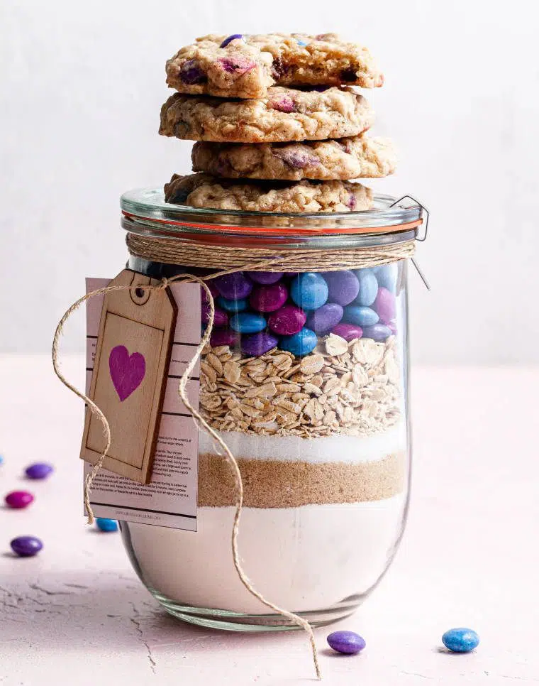 close up of a mason jar on a table with different layers of dry ingredients for a vegan cookie mix
