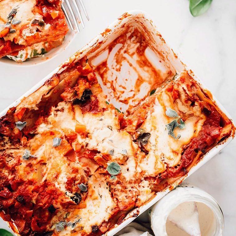 baking dish with creamy dairy free vegan lasagna where a piece has been cut out