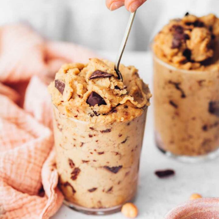 two glass jars filled with chickpea cookie dough with a spoon in one of them