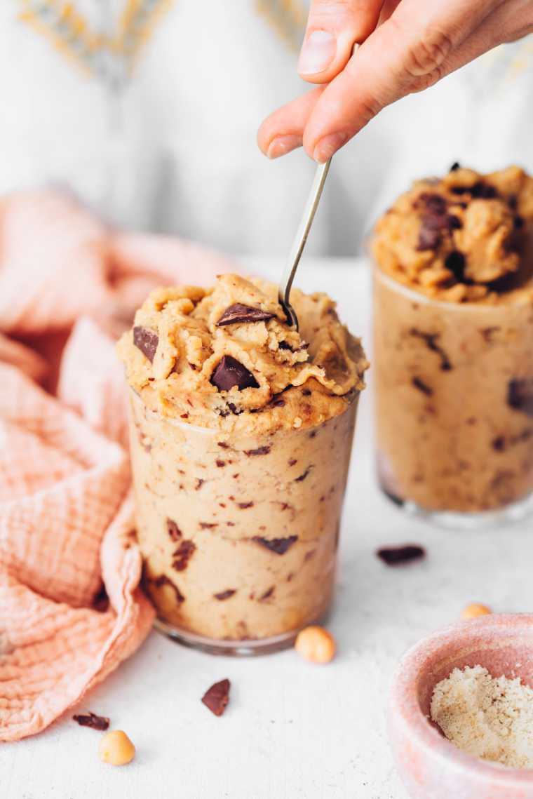 two glass jars filled with chickpea cookie dough with a spoon in one of them