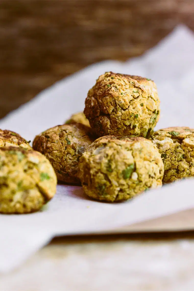 close up of seven freshly baked vegan falafel that are oil-free and golden brown on some parchment paper
