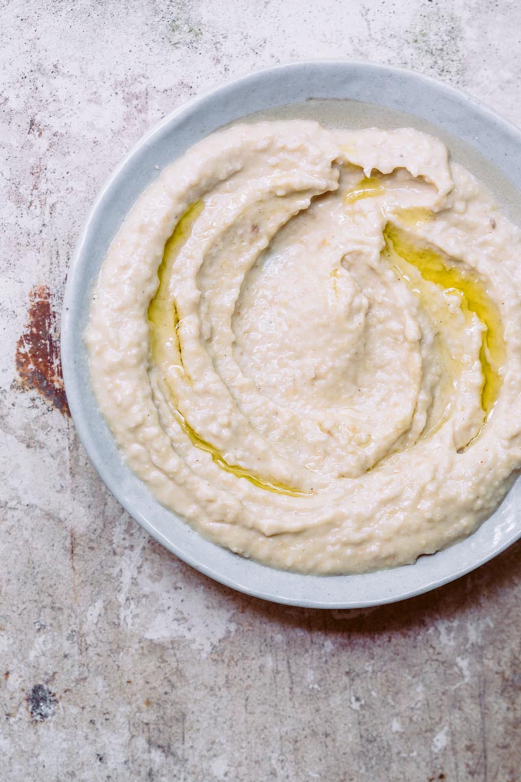 close up of a small bright bowl that's filled with creamy homemade vegan hummus