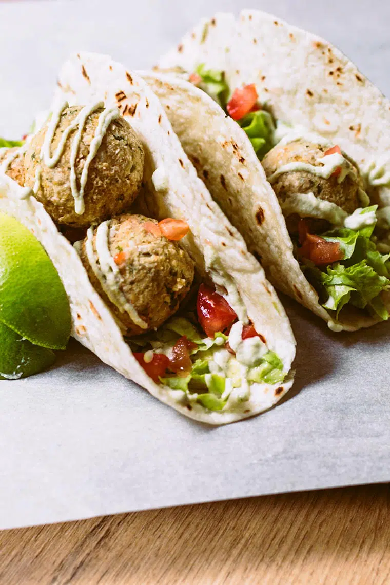 two taco shells that are filled with fresh veggies, baked falafel and drizzled with homemade vegan cashew sour cream