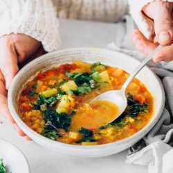 Woman eating from bowl of vegan lentil soup