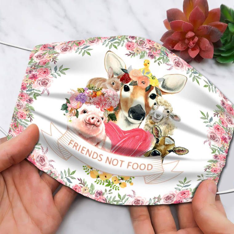 two hands holding a handmade face mask with floral print and five different farm animals alongside the words "friends not food"