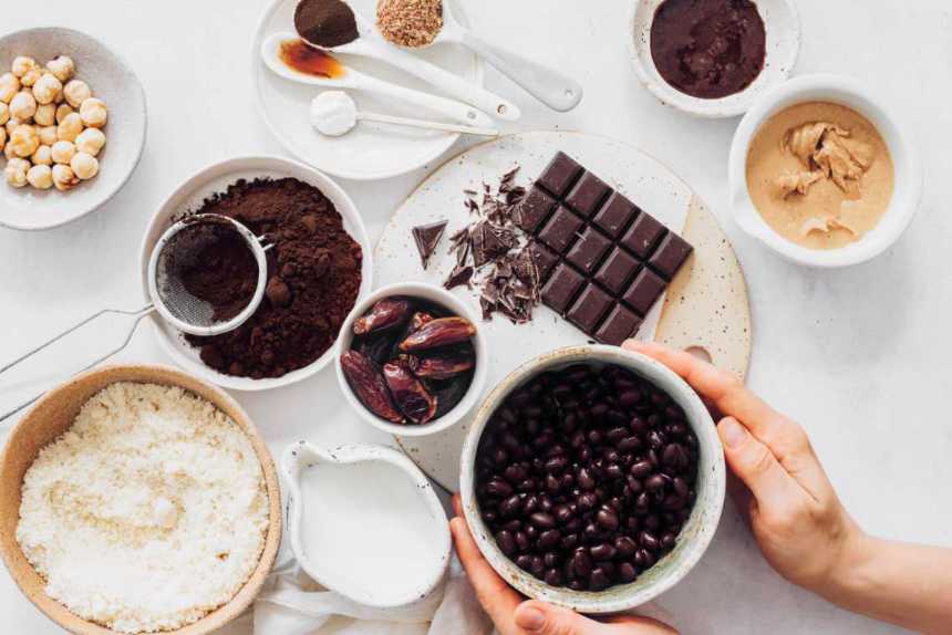 several high-calorie vegan foods on a table from chocolate to flour, beans, dates, coconut milk and peanut butter