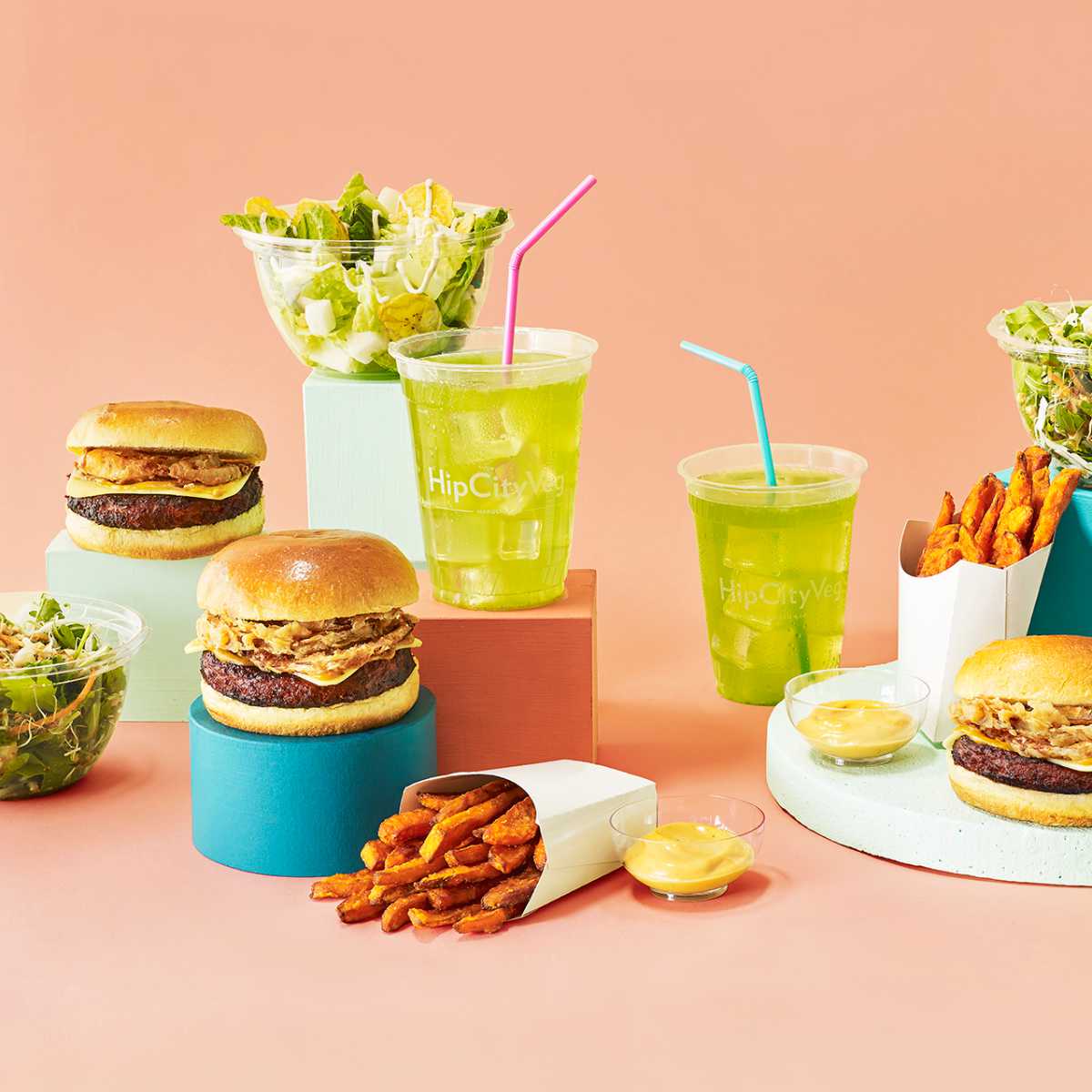 several vegan burgers, salads, fries, and beverages