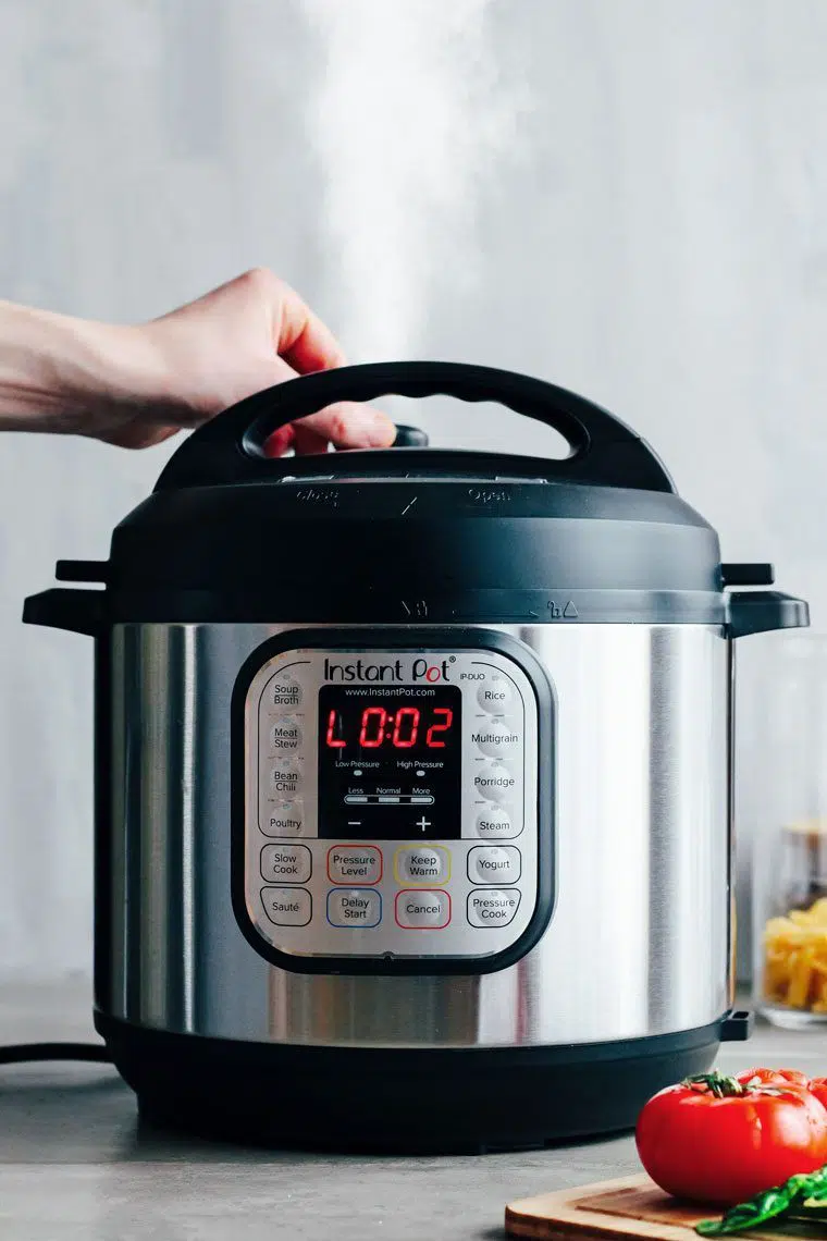Male hand using the pressure valve of an  Instant Pot to release steam