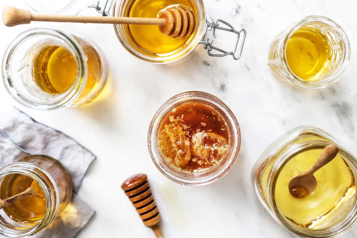 several glass jars with honey on a table