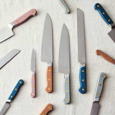 linen with a dozen different-sized high quality knives with colorful handles from blue to green, brown and rose