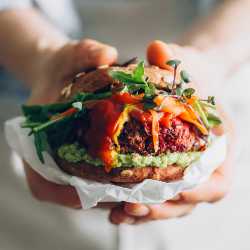 Woman with apron holding vegan burger in hands