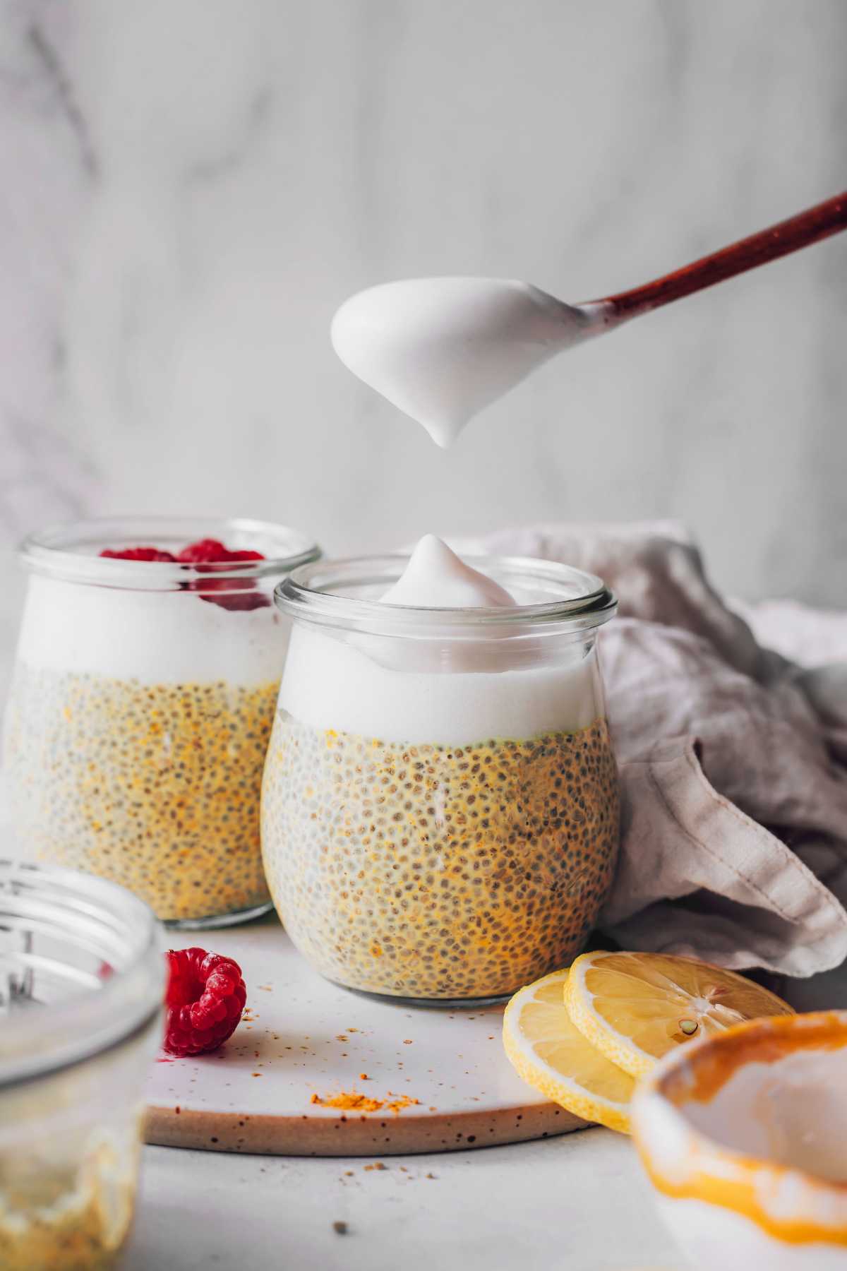 putting whipped cream on chia pudding with a wooden spoon
