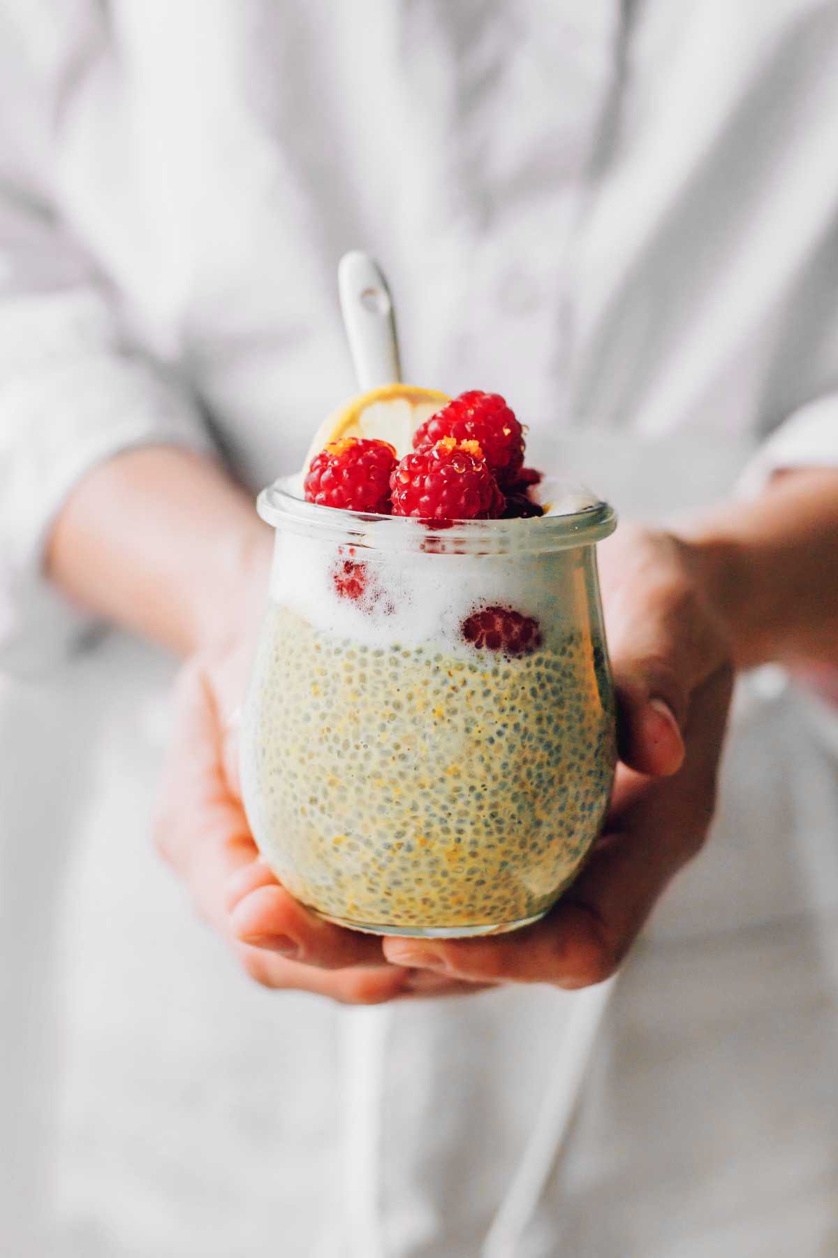 woman holding a glass of vegan lemon chia pudding in her hands